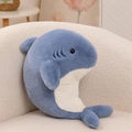 Soft plush blue shark doll stuffed animal toy on a cozy cream bouclé sofa corner - Shark