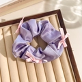 Purple floral scrunchie with silk texture and small pink bows on a beige tray - Purple Band Pink Bow