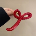 Close-up of a glossy red hair claw clip held against a minimalist beige background - Red (Cross)