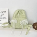 Détail du sac à dos à cordon vert clair avec nœuds en dentelle blanche et texture - Vert