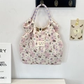 Detail of quilted dog print tote bag with purple checkered woven handles and cloth label - Puppy Paradise