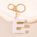 Détail du porte-clés lettre E avec paillettes colorées dans une résine blanche et or - Lettre E