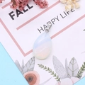 Teardrop opal stone pendant with silver clasp on decorative floral card background - Opal