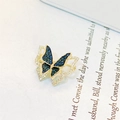 Squisita spilla a farfalla dorata con zirconi blu e trasparenti su carta bianca - Blu scuro