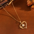 Gros plan d'un collier pendentif cœur doré avec pierre précieuse et petits diamants - Collier Cœur Fleur Zircon Blanc Doré