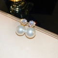 Macro shot of elegant gold flower earrings with sparkling zircons and white pearls - Round Zirconia Pearl Drop