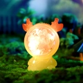 Orange deer night light with white dried flowers and LED glow in forest setting - Yellow Antler Lamp