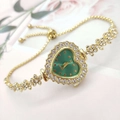 Dettaglio macro di un orologio d'oro a forma di cuore con quadrante verde e strass - Oro Verde
