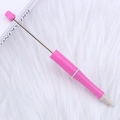 Pink DIY beaded ballpoint pen with metallic rod on a soft white plush background - Eco Purplish Red