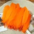 Natural bright orange goose feathers for DIY crafts on a beige woven mat background - Stiff Orange Red (50Pcs)