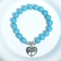 Blue turquoise beaded bracelet with silver heart tree of life charm on white surface - Blue Turquoise Tree of Life Charm