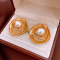 Primer plano de pendientes vintage dorados con diseño de remolino y una perla blanca - Dorado