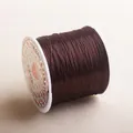 Macro view of strong brown crystal stretchy elastic cord for DIY jewelry on white spool - Coffee