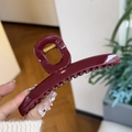 Detail of burgundy large hair claw clip with glossy resin finish and gold spring - Ancorra Red