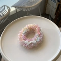 Détail d'un chouchou en dentelle multicolore aux textures de maille rose et bleu pastel - Ton Rose Clair