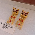 Close-up of Chinese lion dance tassel earrings with red beads and golden coin details - 925 Silver Pin Earrings - Gold
