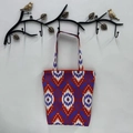 Close-up of purple and red ikat pattern canvas tote bag hanging on a decorative hook - Dark Red