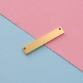 Close-up of a gold mirror-finish stainless steel rectangular tag with double holes - 2*6*35mm / Gold