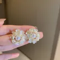 Detailopname van witte pareloorbellen met handgemaakte harsbloemblaadjes rondom - Vijfbladige Bloem Stijl / Wit