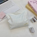 Detailed close-up of blue-green checkered makeup bag with woven fabric texture and label - Soft Purple Plaid