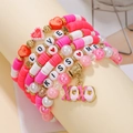 Close-up of bohemian heart charm bracelets with red and pink Heishi beads and XOXO pendant - Red Pink XOXO/LOVE Heart Combo