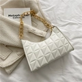 Detail der weißen gesteppten Handtasche mit goldener Kette auf Tweed-Jacke und Buch - Weiß