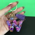 Pink resin letter W keychain with colorful stones, purple tassel, and gold-tone metal ring - Letter W