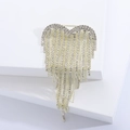 Dettaglio ravvicinato di una spilla a cuore dorata con nappe e strass brillanti su sfondo bianco - Oro