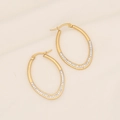 Elegantes pendientes de aro ovalados dorados con cristales blancos en fondo beige textil - Ovalado