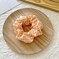 Cute orange and white checkered scrunchie hair tie presented on a wooden tray - Dark Yellow Plaid