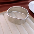Vista macro dell'ampio bracciale in metallo argentato martellato con dettagli riflettenti - Martellato Largo (Argento) / Argento