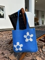 Detail of blue knitted tote bag with large floral patterns on a wooden garden chair - Sapphire Blue