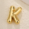Macro shot of 3D balloon style letter K pendant with polished gold finish on stone - Letter K