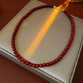 Détail d'un collier de perles rouges avec fermoir doré sur un support minimaliste - Diamètre 6mm