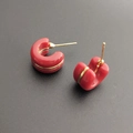 Primer plano detallado de pendientes rojos en forma de C con ribete dorado y plata S925 - Burdeos