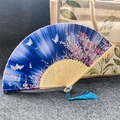 Classic folding fan with dark blue fabric featuring pink cherry blossoms and blue tassel - Butterflies Flying Blue - Light Handle