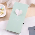Biglietto d'auguri verde menta con cuore 3D bianco su sfondo di rivista e dolci - Cuore 3D / Verde