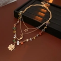Détail de collier doré multi-rangs avec pendentifs soleil, lune, étoile et pierres - Or (Ensemble de 3 pièces)
