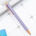 Purple and gold metal ballpoint pen with scale pattern resting on a book - Water Drop Purple (Rose Gold Trim)
