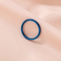 Detalle de un anillo minimalista de acero de titanio azul sobre tela rosa texturizada - US 6 / Azul