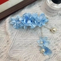 Blue fabric flower hair clip with pearl pendants displayed on white lace fabric - Blue Camellia Hair Clip