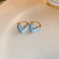 Macro shot of sky blue heart-shaped earrings with golden edges on a textured tray - Pearlescent Sky Blue Heart (HE22001)