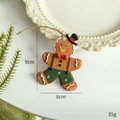Gingerbread man ornament with green overalls and black hat on festive pine background - Suspenders Gingerbread Man