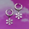Macro shot of silver stainless steel hoop earrings with polished six-petal flower charms - Petal