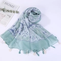 Close-up of light blue-green patterned shawl with fringe trim on a white background - Style 21