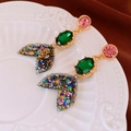Detalle de pendientes de sirena con piedras sobre un plato de cerámica blanca - Pendientes de Cola de Sirena con Diamantes de Imitación en Contraste de Color