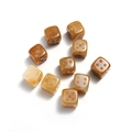 Detailed close-up of nine 15mm natural stone dice with clear dot engravings on white background - Topaz