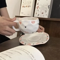 Close-up of handmade ceramic coffee cup with pink heart pattern on a wooden table - Sweet Cool Heart
