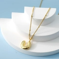 Golden bubble letter U pendant necklace with a fine beaded chain on a blue background - Letter U(U)