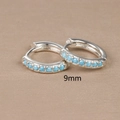 Detail shot of 9mm silver hoop earrings featuring a small round blue zircon stone - 9mm / Silver (Blue Zirconia)